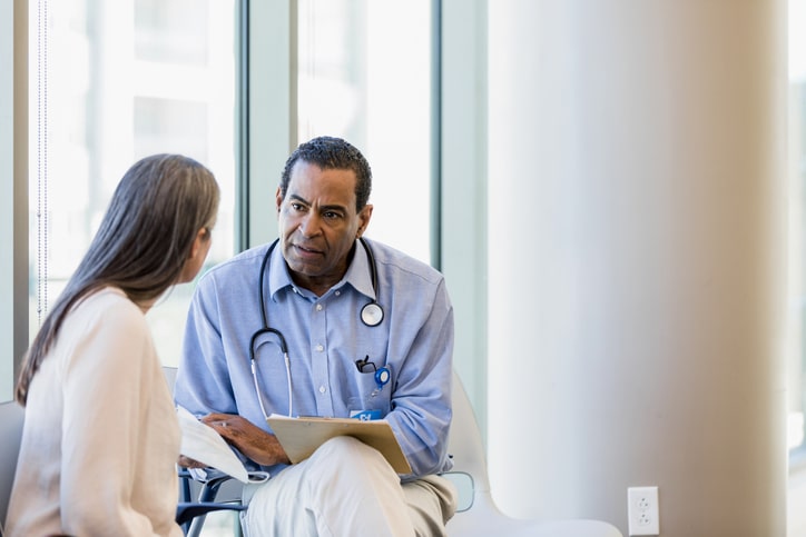 Serious male doctor listens to unrecognizable woman