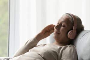 Older woman wearing headphones and relaxing on a sofa