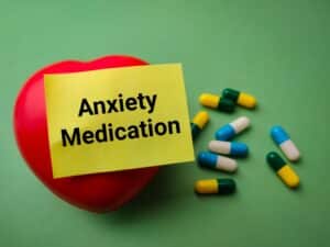 Sticky note saying anxiety medication on an apple with pills around it.