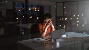 A woman sits overwhelmed in front of her computer.