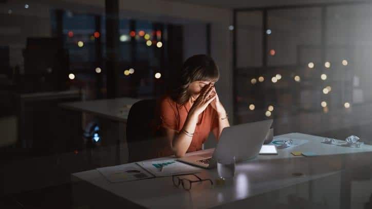 A woman sits overwhelmed in front of her computer.